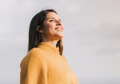 smiling-young-woman-standing-against-sky-looking-away